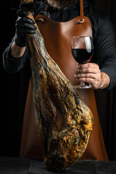 cutting specialist cortador holds Iberian ham pata negra, Dry Spanish ham, Jamon Serrano, Bellota, Italian Prosciutto Crudo or Parma ham
