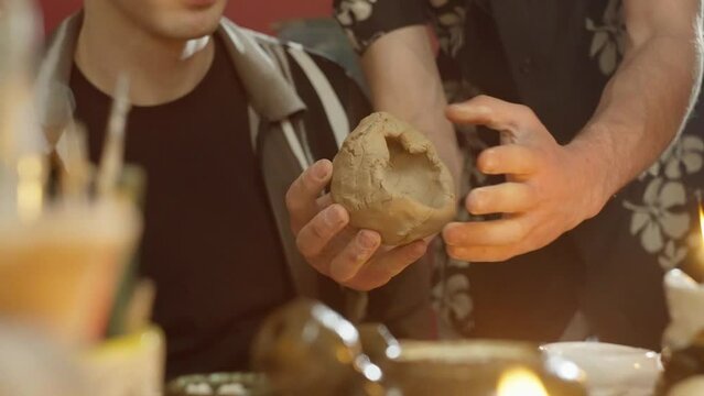 Close-up of master's hands helping students sculpt ceramics from clay. Occupation and hobby of pottery in the workshop. High quality 4k footage