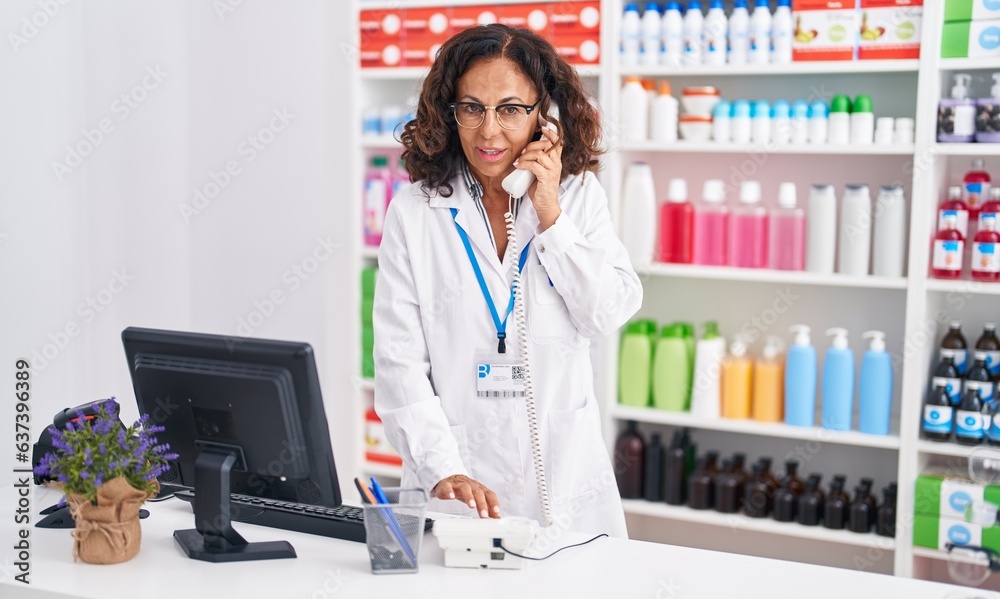 Sticker Middle age woman pharmacist talking on telephone at pharmacy