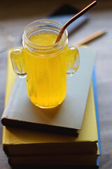 Plate of chocolate chip cookies, stack of books, reading glasses, orange soda, mobile phone and pen on the table. Hygge at home. Pastel colors, selective focus.
