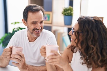 Man and woman couple drinking coffee sitting on table at home