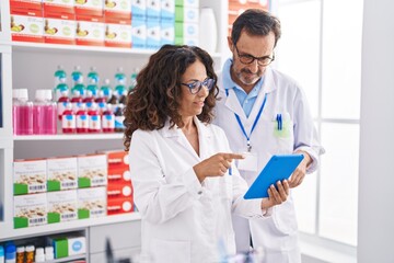 Man and woman pharmacists using touchpad working at pharmacy
