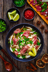 Pho soup - Vietnamese soup with beef on wooden table
