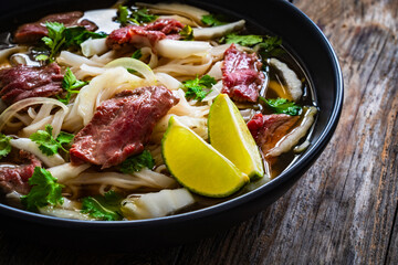 Pho soup - Vietnamese soup with beef on wooden table
