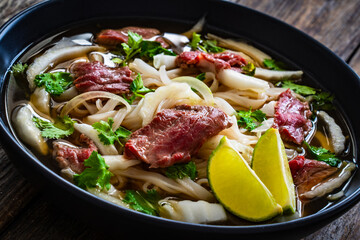 Pho soup - Vietnamese soup with beef on wooden table
