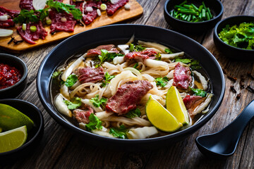 Pho soup - Vietnamese soup with beef on wooden table
