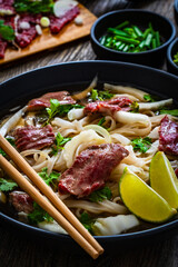Pho soup - Vietnamese soup with beef on wooden table

