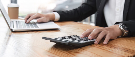 Business man using a calculator to calculate and analysis the company financial tax budget and income.