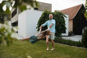 Father holding daugter and spinning her around in the garden.