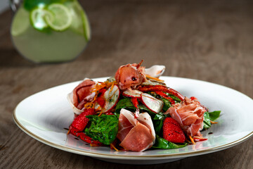 salad with ham, spinach and mozzarella on wooden table