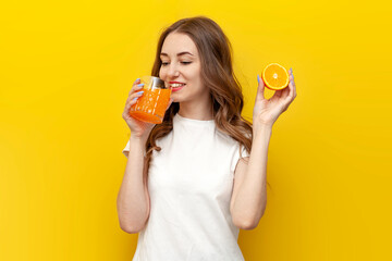 young girl with orange drinks orange juice from glass on yellow isolated background, woman with drink and citrus fruit