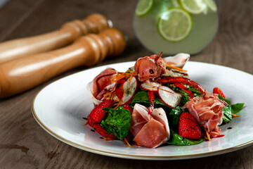 salad with ham, spinach and mozzarella on wooden table