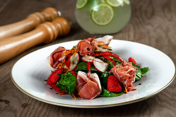 salad with ham, spinach and mozzarella on wooden table