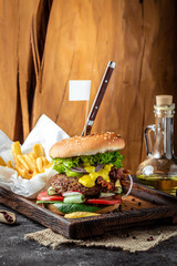 Homemade burger with a juicy cutlet, cheese sauce and salad, vertical image. top view. place for text