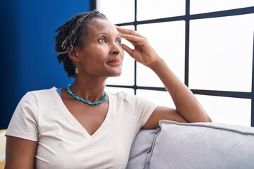 Middle age african american woman sitting on sofa with serious expression at home