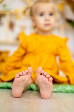 the legs of a small child in yellow clothes on the floor in focus
