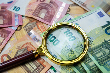 magnifying glass on different euro bills as background. Finance concept