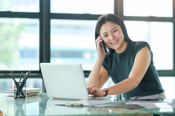 Fototapeta premium Attractive asian businesswoman talking with her business partner while sitting in modern office.