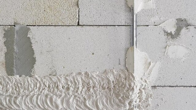 Machine plastering. Applying gypsum plaster by mechanized method on the surface of foam blocks. 
