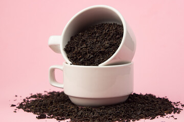 Loose tea in a white cup on a pink background