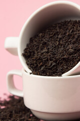 Loose tea in a white cup on a pink background