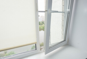 The double-glazed window is white with roller blinds. The window is not opened correctly. window repair, breakage.