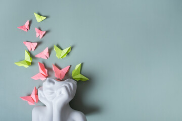 A figurine of a head with butterflies on a colored background. Overthinking. Mental health concept....