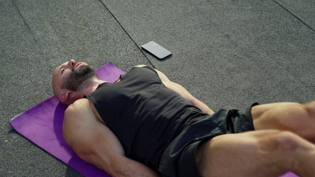 A man practices fitness on a mat outside. Heavy exercises for sport muscular athletic guy working hard. High quality 4k footage