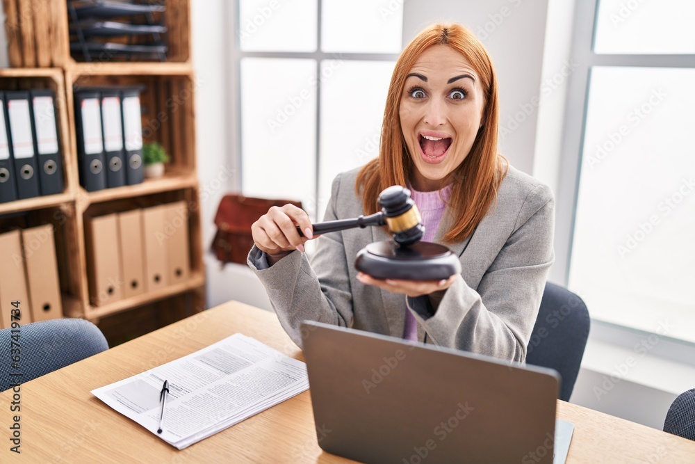 Canvas Prints Young business woman using gavel celebrating crazy and amazed for success with open eyes screaming excited.