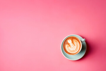 A cup of cappuccino with latte art on pink background. Top view with copyspace for your text.  A morning drink sitting on top of a table.  - 637420300
