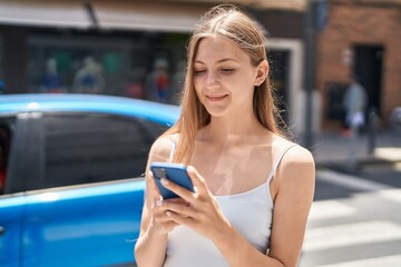 Young caucasian woman smiling confident using smartphone at street