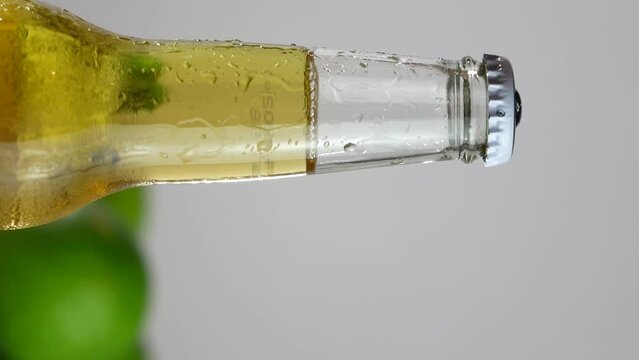A bottle of light Mexican beer. Vertical video for reels. Bottleneck and lime in the background