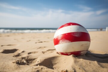 A vibrant red and white ball resting on a pristine sandy beach