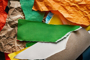 Abstract photo composition made from colorful pieces of torn crumpled textured paper. Green piece in center as copyspace. Reuse paper trash to create a new collage