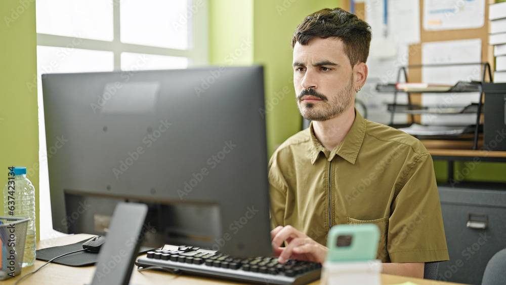 Wall mural Young hispanic man business worker using computer working at office