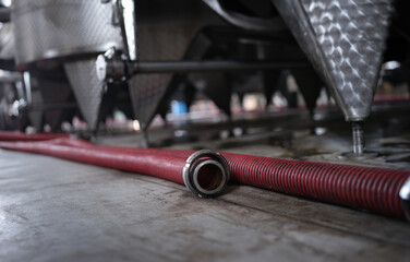 Red rubber hose lies on floor in industrial factory. Various mechanisms for filling various...