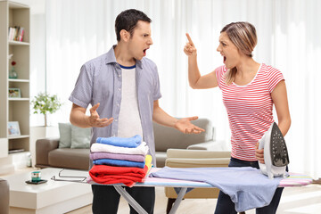 Young couple arguing behind an ironing board at home
