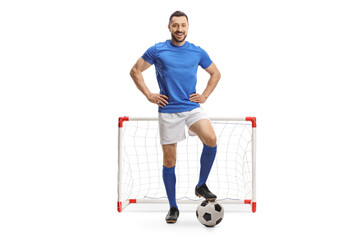 Full length portrait of a soccer player posing with a ball in front of a mini goal