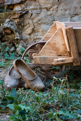 Rural scene, wooden clogs, galochas, leaning on a work wheelbarrow in a courtyard of a Castilian house
