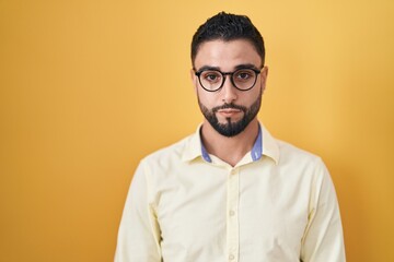 Obraz premium Hispanic young man wearing business clothes and glasses relaxed with serious expression on face. simple and natural looking at the camera.