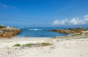 Fototapeta na wymiar small cove on the coast with a semicircular beach and waves breaking on the rocks