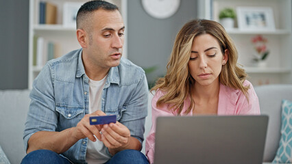 Man and woman couple shopping with laptop and credit card sitting on sofa at home