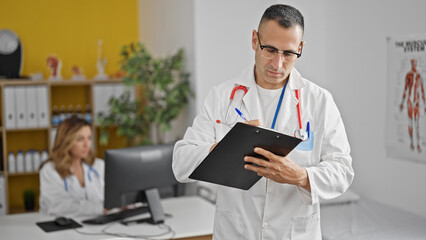 Man and woman doctors writing medical report using computer working at the clinic