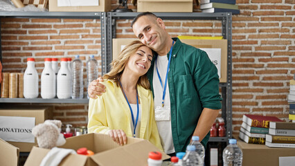 Man and woman volunteers hugging each other smiling at charity center