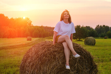 Naklejka na ściany i meble Agriculture and fun come together in this full length photo of an adult woman playing in a haystack. Portrait of a happy 35 year old woman