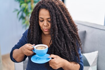 African american woman drinking coffee sitting on sofa at home