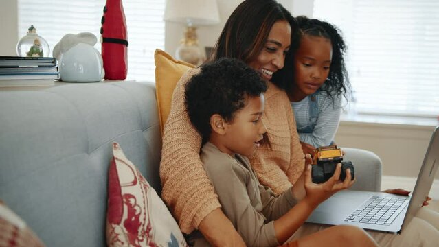 Mom and children having a family video call at home, with her son showing his new toy on the call. Family of three using technology to stay connected with dad and spend some online family time.
