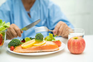 Asian elderly woman patient eating salmon steak breakfast with vegetable healthy food in hospital.