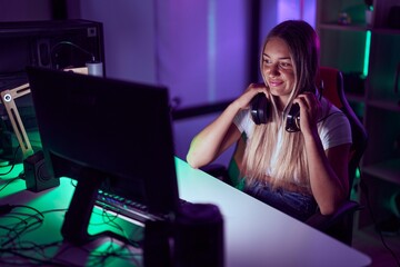 Young beautiful hispanic woman streamer smiling confident wearing headphones at gaming room © Krakenimages.com
