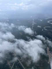 Obraz premium The image below is viewed from an airplane through the clouds. Green ground full of trees interspersed with people's houses and land.